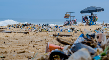 plastic waste cover a beautiful beach under the blue sky with a life guard sitting far away