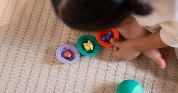 a top down photo of a child plays with b is for ball with other natural materials