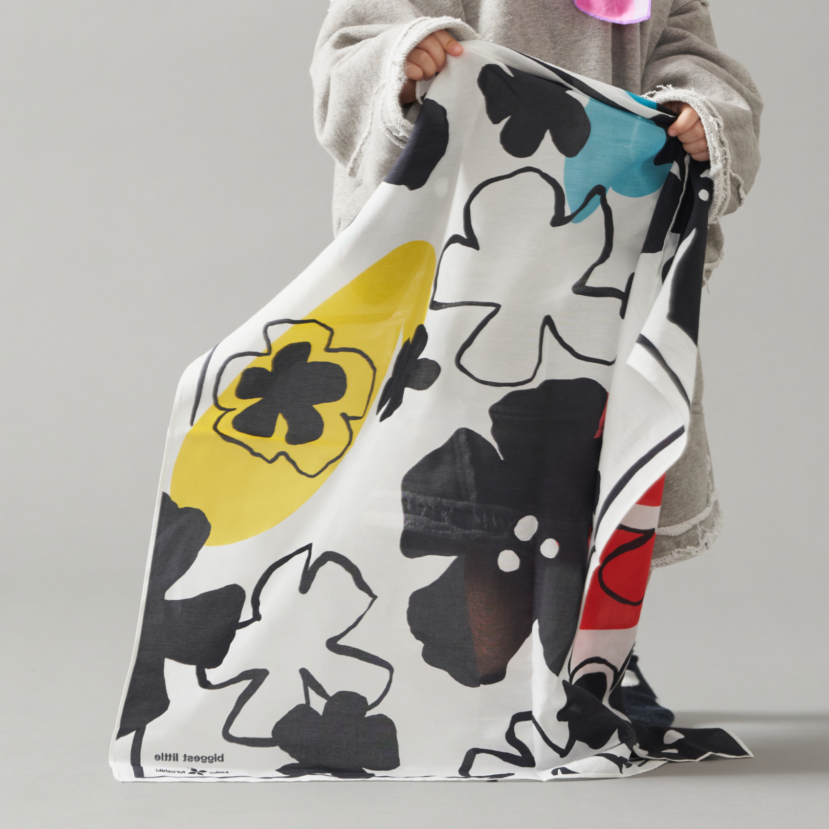Toddler holding a art play silk in secret garden print letting it drapes naturally on the ground