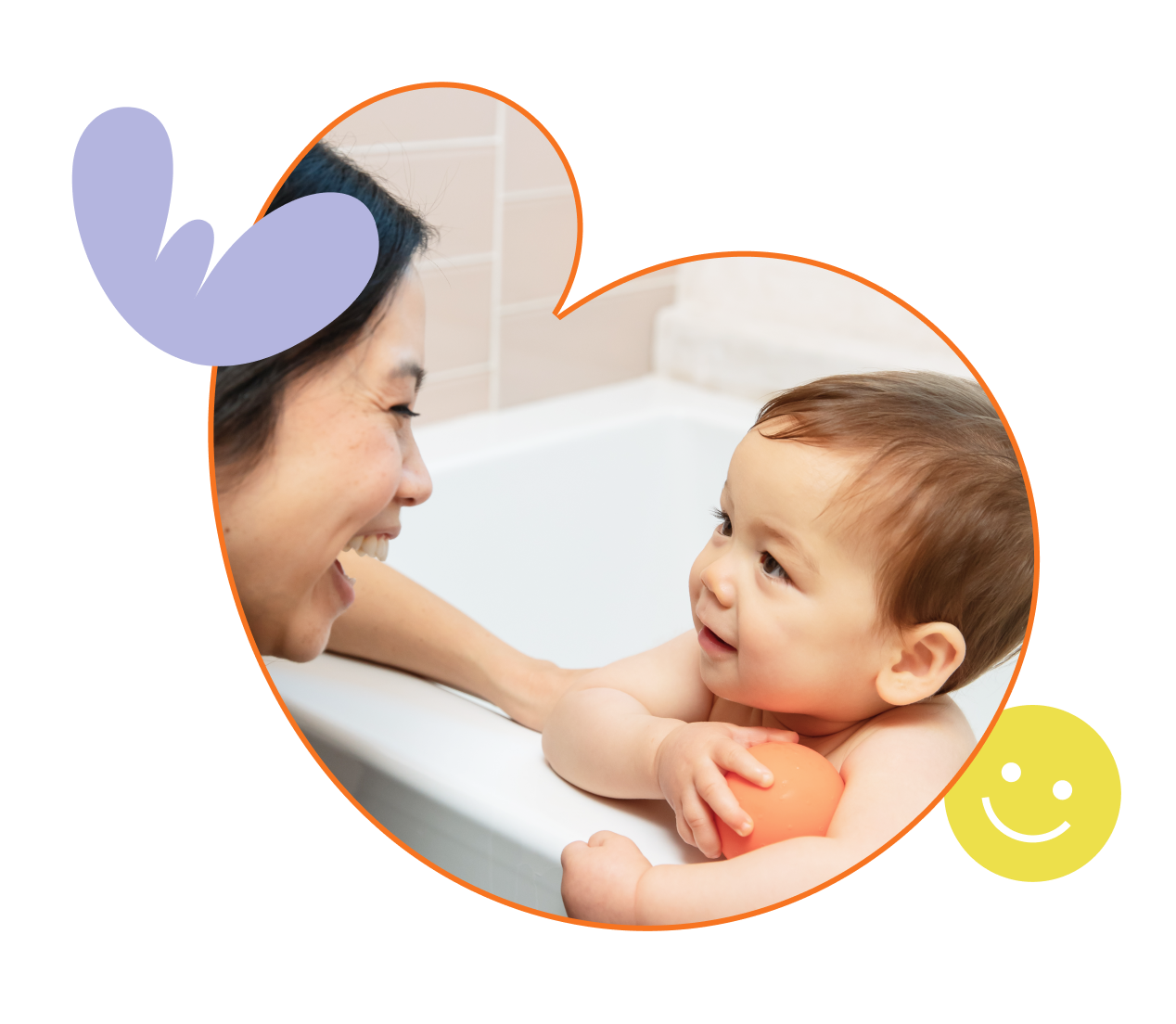 Mom is smiling at her baby boy who is holding an orange bath toy ball
