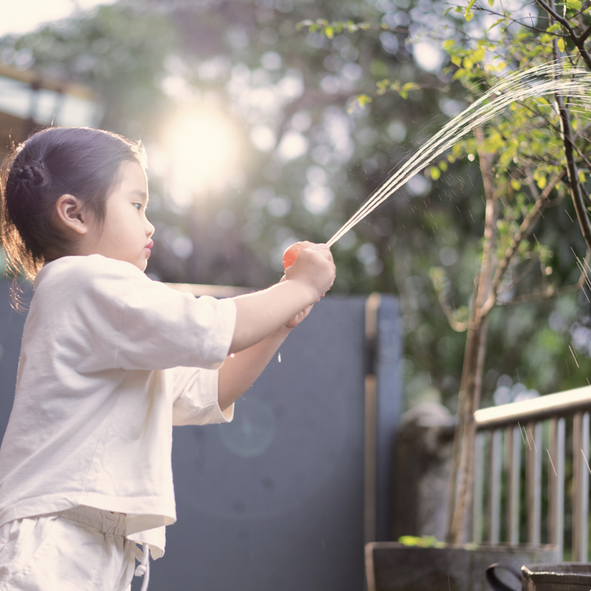 Toddler squirting water from B is for Ball toy for sensory play