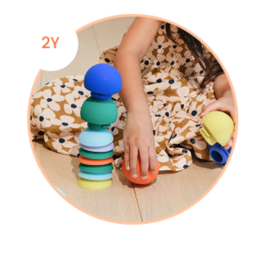 close up of a pair of hands holding a b is for ball® and a pile of b is for ball® stacked together showcasing a 2 year old use it for stacking and balance